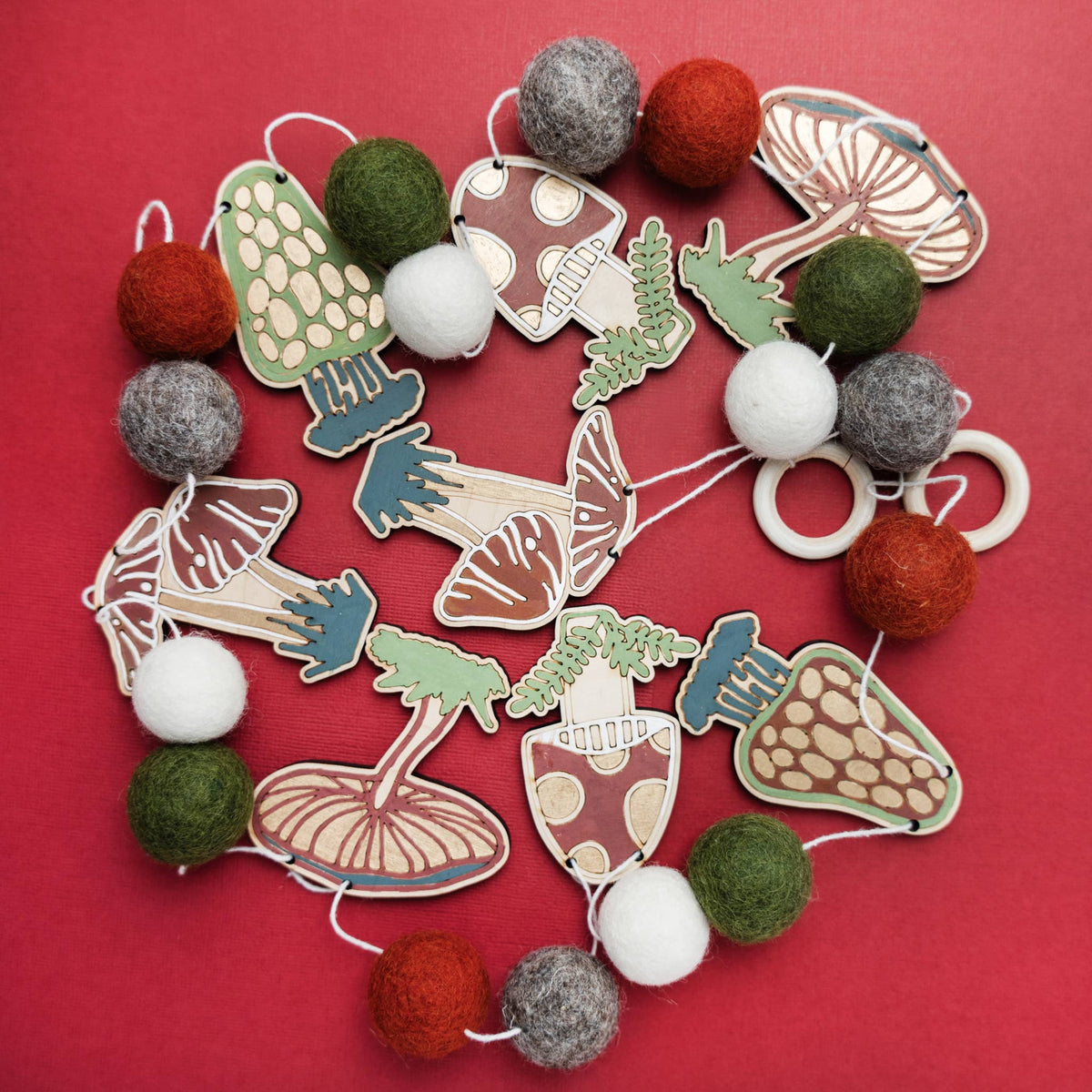 Painted wooden mushroom cutouts and felt balls for a DIY garland