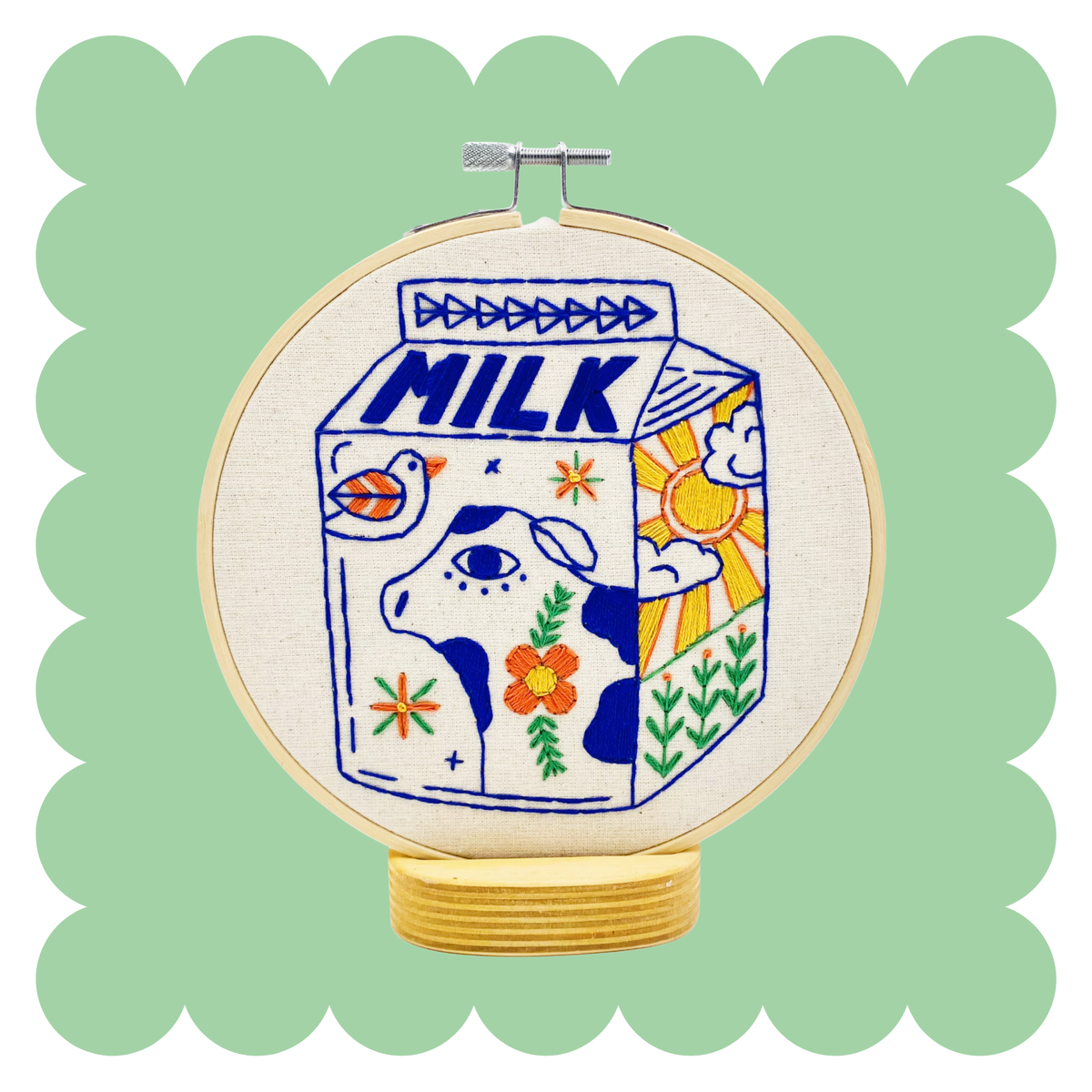 Embroidery hoop with stitched retro milk carton and cow in blue