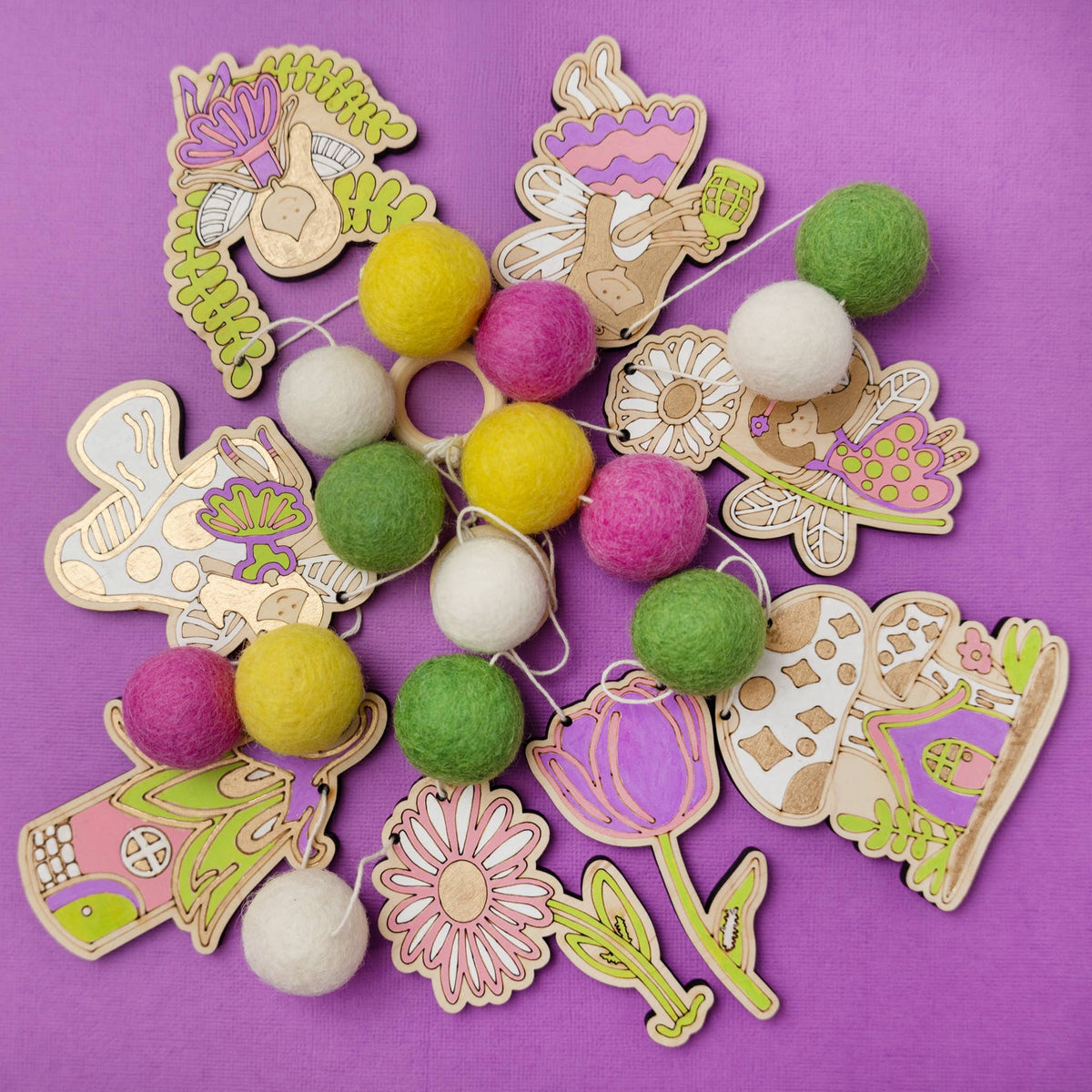 Painted wooden fairy and flower house cutouts with felt balls for a DIY garland