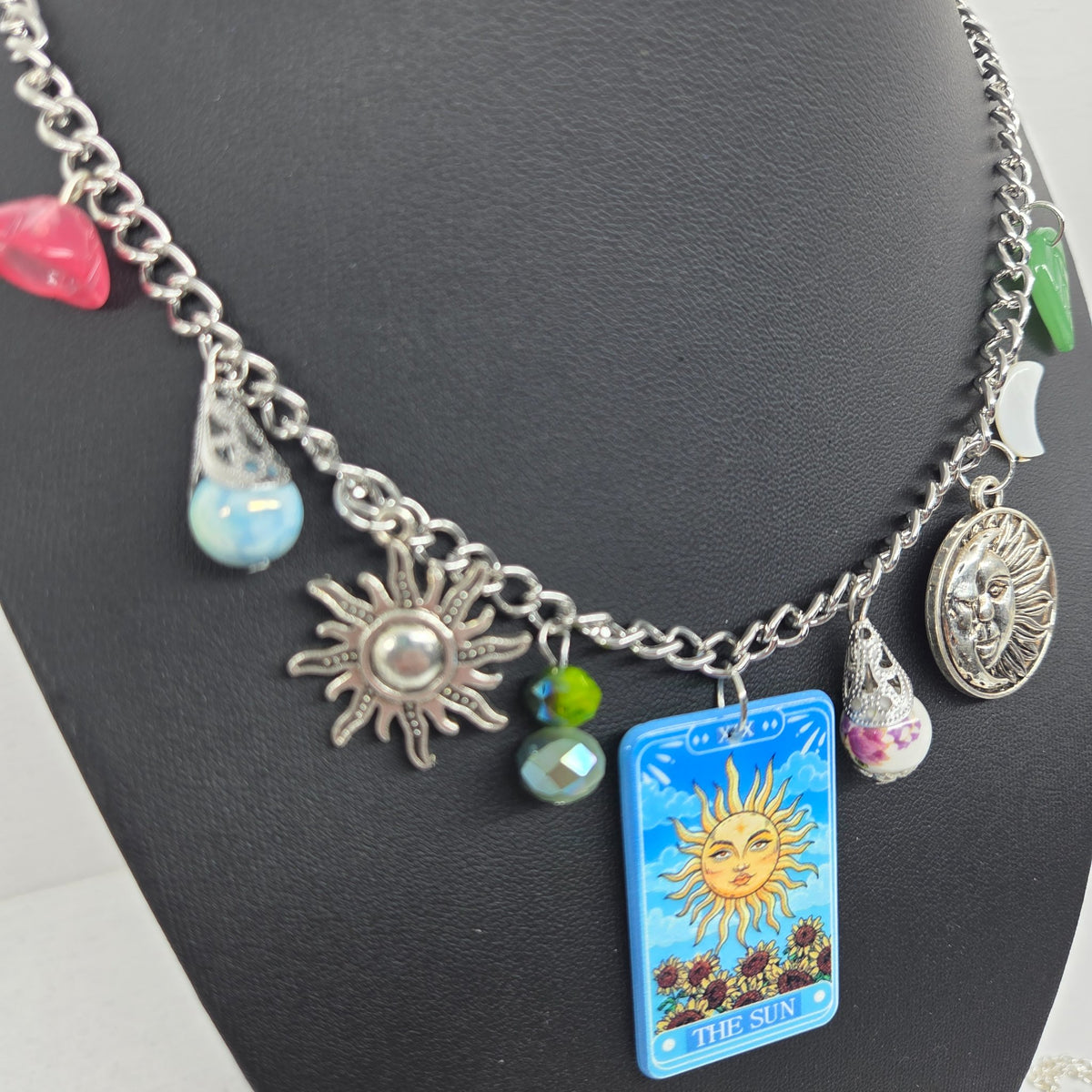 Second view of The Sun charm necklace showing its nature and celestial charms
