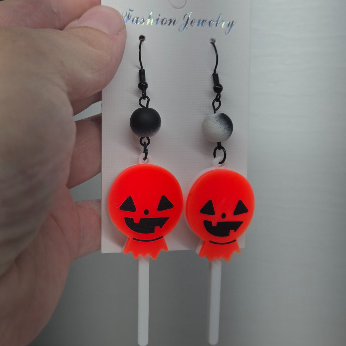 Pumpkin lollipop earrings measuring four inches from the hook, handmade by The Velvet Viper