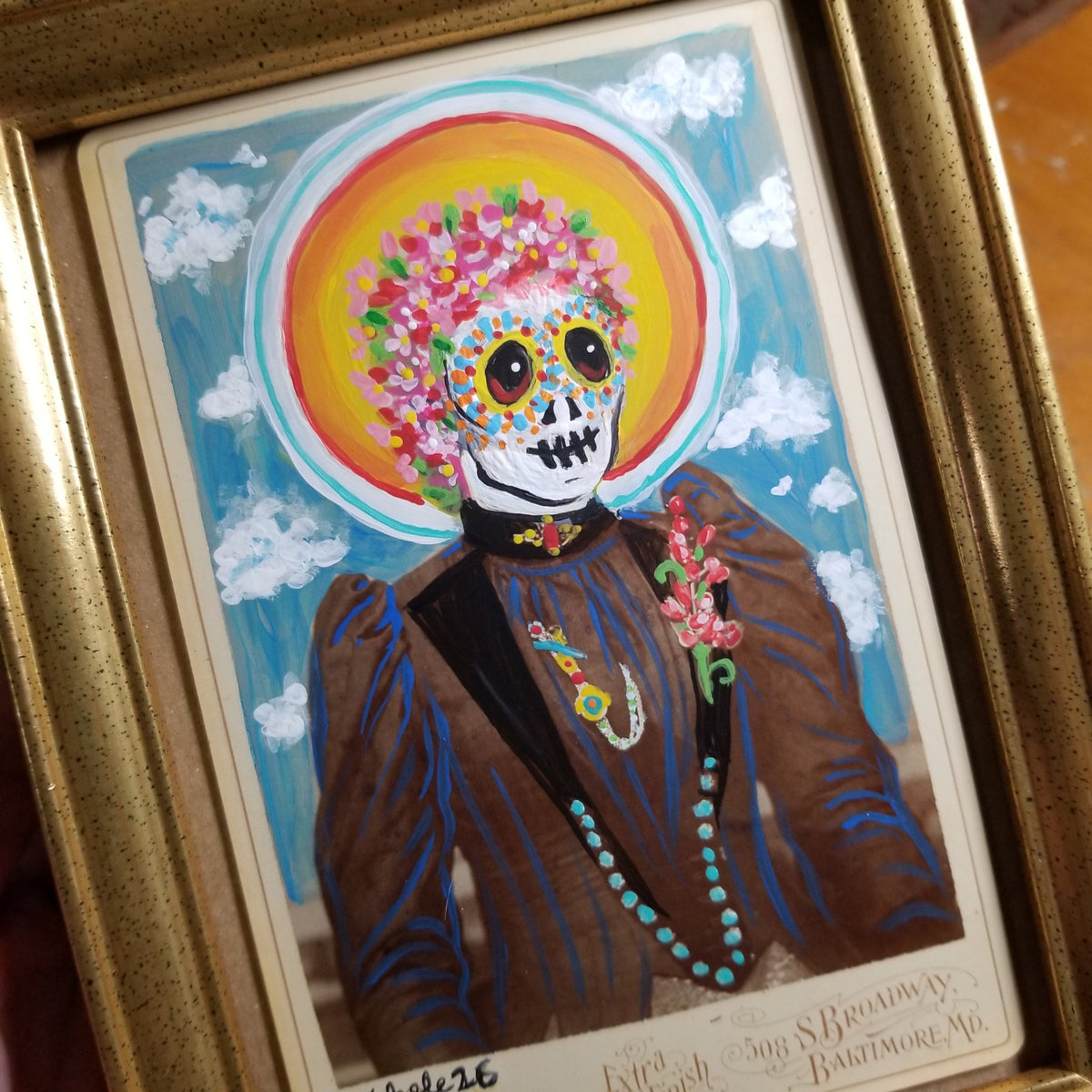 Third view of La Catrina showing the gold frame and vintage postcard base