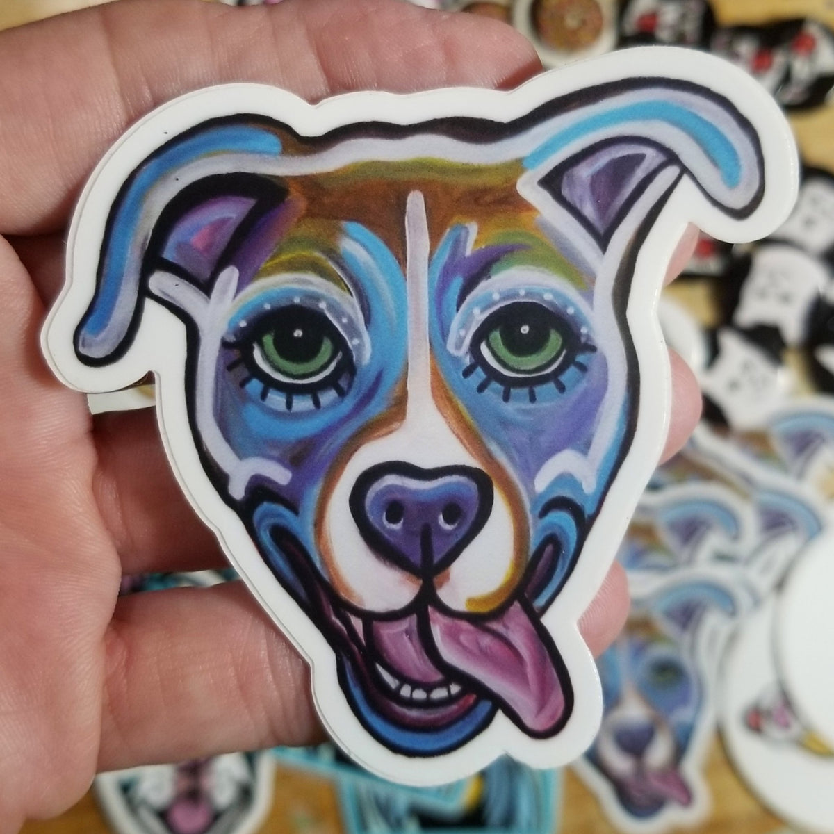 Blue and purple dog with its tongue out on a durable vinyl sticker by Michele The Painter