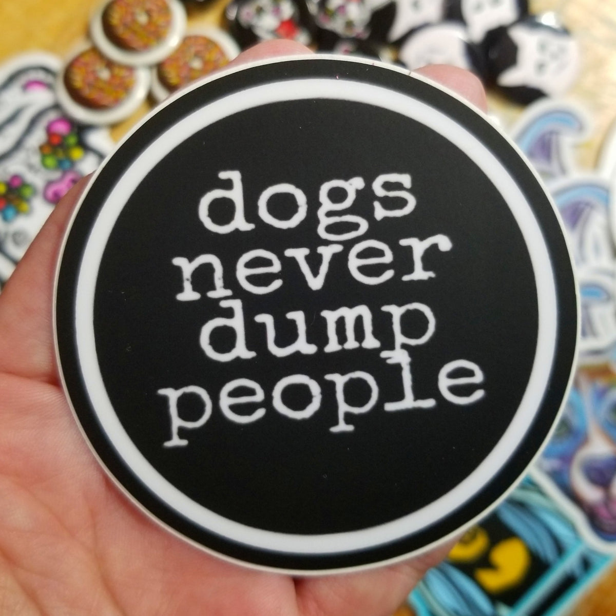 Vinyl sticker reading Dogs Never Dump People, original art by Michele The Painter