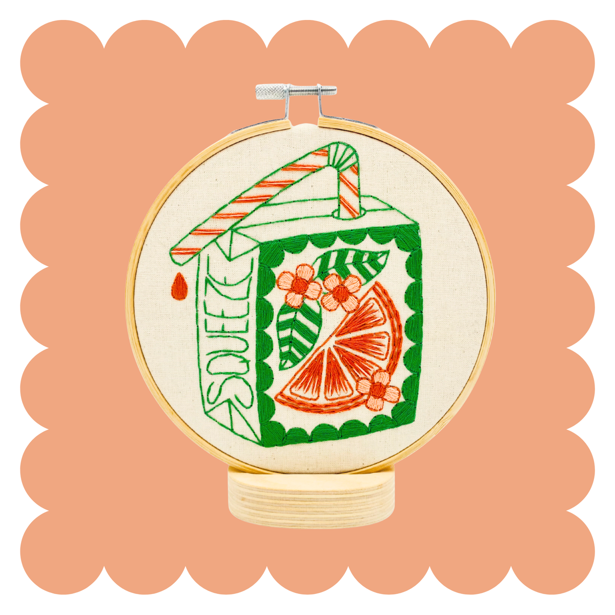 Embroidery hoop with stitched retro orange juice box pattern in orange and green