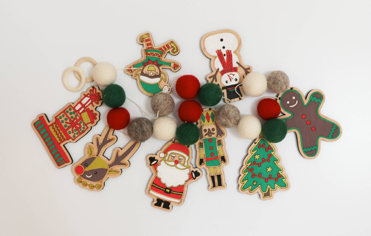 Painted wooden Santa, reindeer and Christmas cutouts with red and green felt balls for a DIY garland